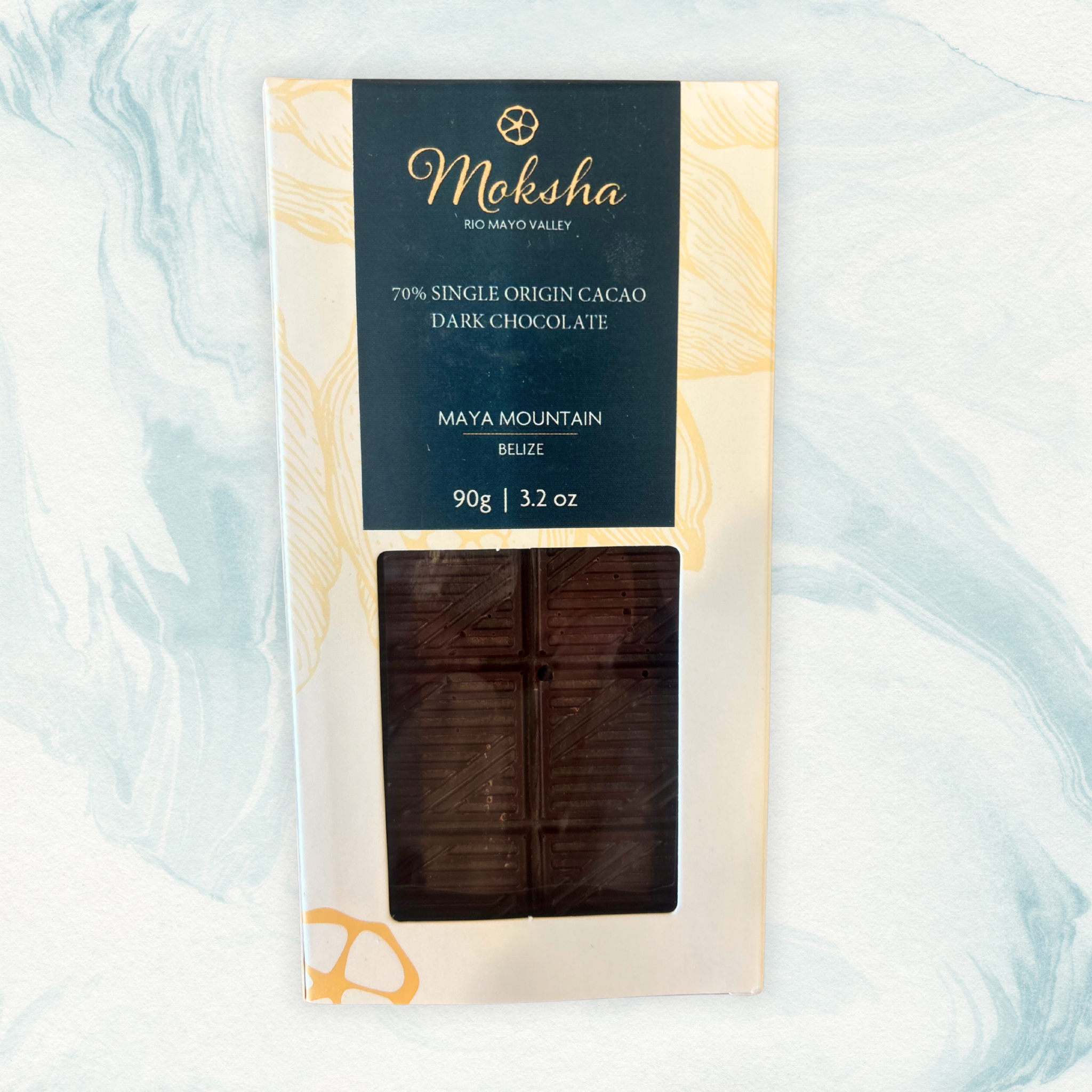 Moksha Chocolate 70% Single Origin Cacao Dark Chocolate from Maya Mountain, Belize, in white and navy blue packaging with a clear window showing the dark chocolate bar.