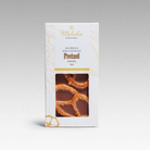 Moksha Chocolate 50% Criollo Mylk Chocolate Pretzel bar from Shanao, Peru, in white and gold packaging with a clear window revealing salted pretzels embedded in vegan mylk chocolate.